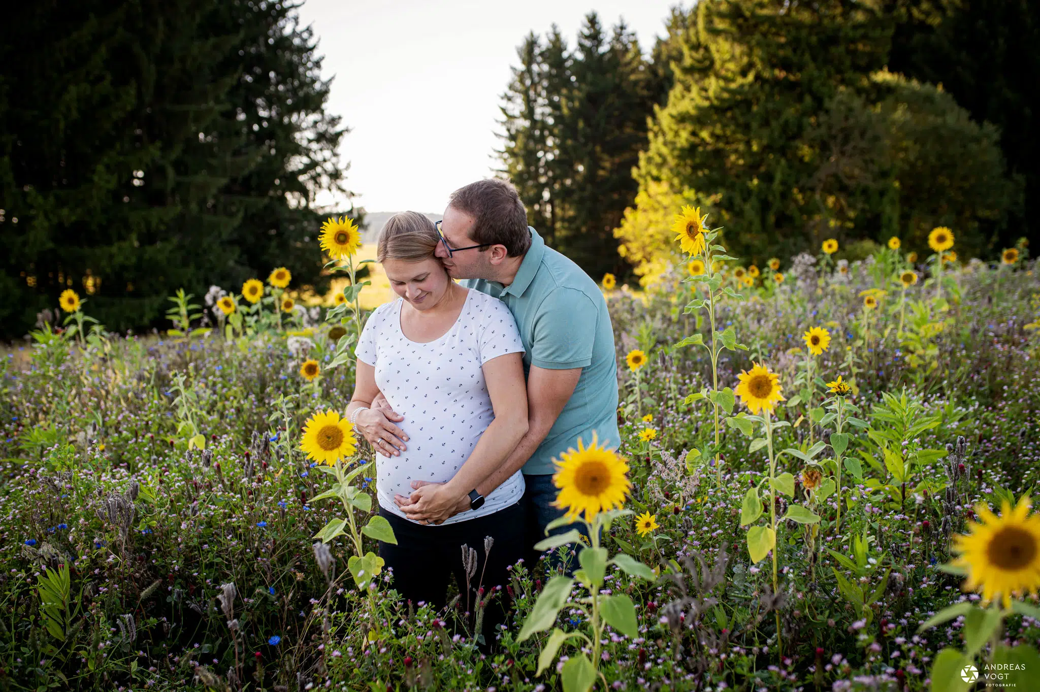Babybauchfoto mit Partner in einem Sonnenblumenfeld - Fotograf Andreas Vogt aus Aalen